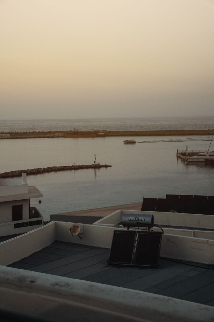 Serene coastal scene at sunset featuring a rooftop solar panel and tranquil waters.