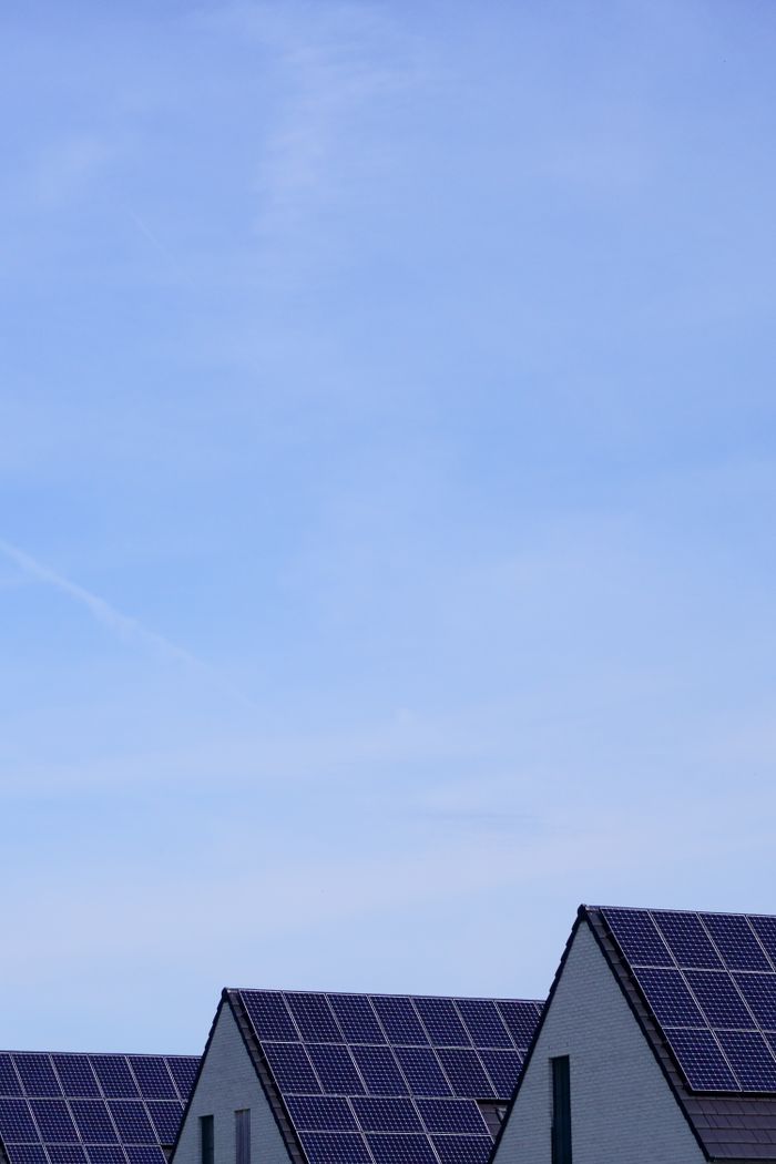 Modern residential houses with solar panels under clear blue sky, promoting renewable energy.